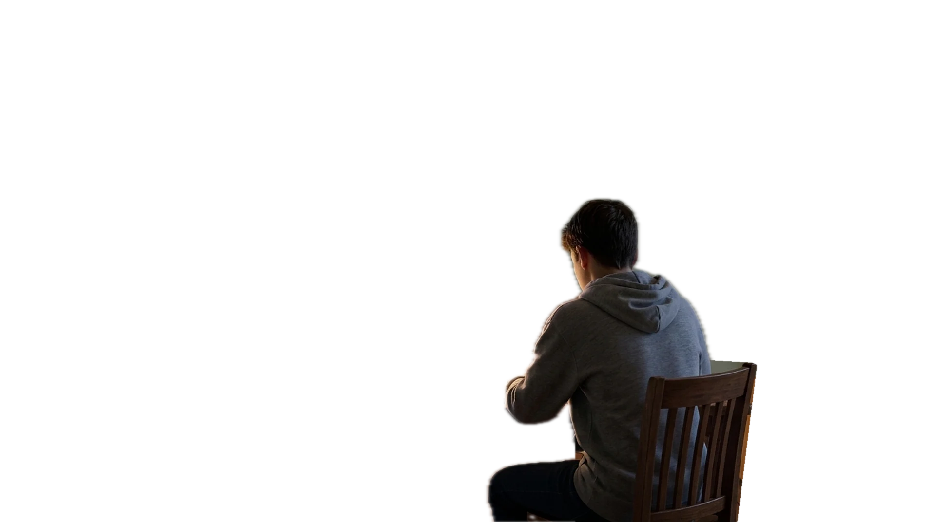 Seen from a doorway at dusk, a teenager sketches at a desk under a lamp